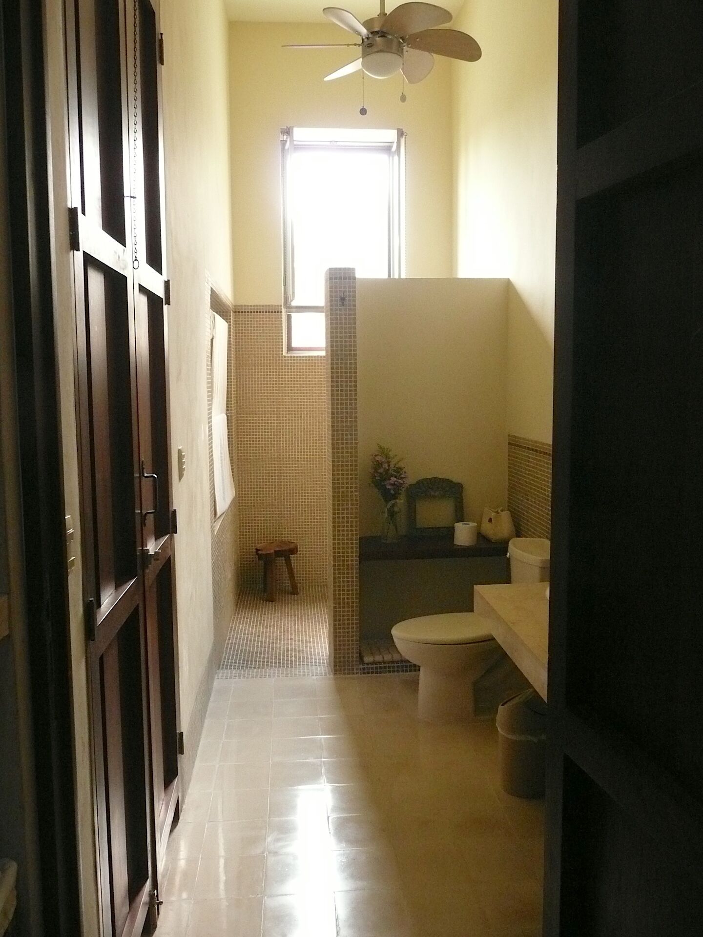 Une petite salle de bain comprenant des toilettes, un lavabo et un petit tabouret.
