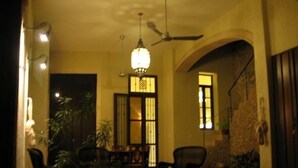 A dimly lit room with a dining table and chairs, a ceiling fan, and a staircase leading to an upper level.