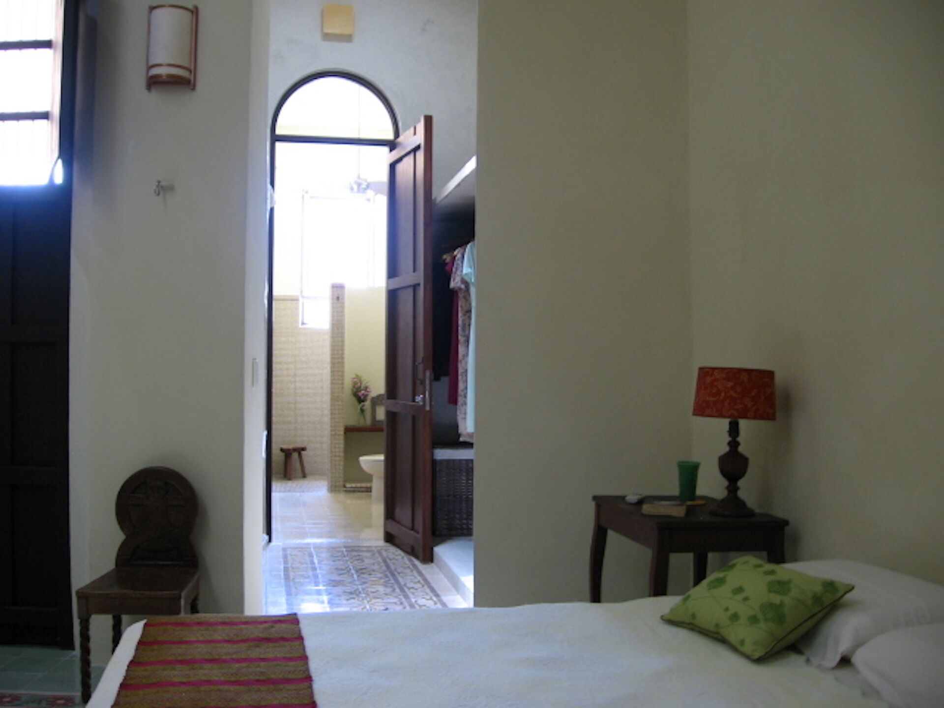 A bedroom with a bed, a nightstand, a chair, and a lamp.