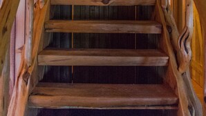 A wooden staircase with a rustic design, leading to an upper level.