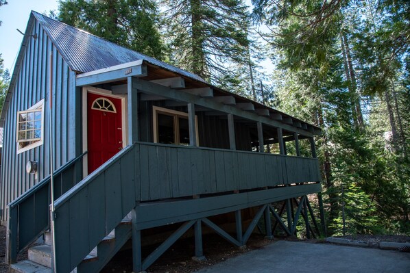A wooden cabin with a red door and a small porch.