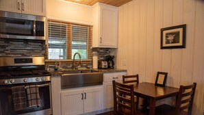 A kitchen with stainless steel appliances, a wooden dining table, and white cabinetry.