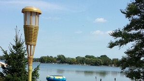 A grassy area with a lamp post, a dock, and a boat on a lake.
