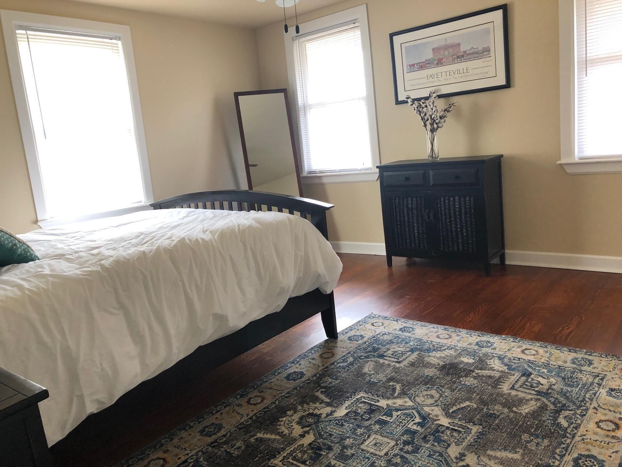 A bedroom with a bed, a dresser, a mirror, and a rug.