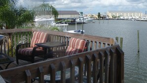 A wooden deck with outdoor seating, overlooking a marina with boats and buildings in the background. - Family Owned Waterfront 3 Bedroom/2 Bath Fully Furnished Condo (Venice)