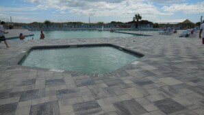 Un espace piscine comprenant plusieurs bassins et des chaises longues.