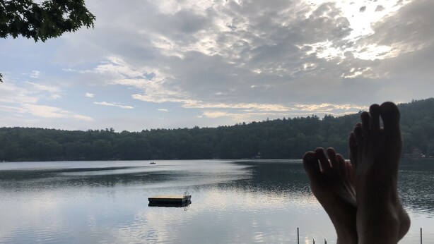 Un lac avec un quai et un bateau visible au loin.