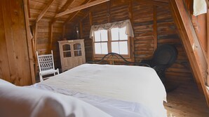 Une chambre dans une cabane en bois, avec un lit, une chaise et une fenêtre.