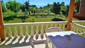 A balcony with a table and chairs, overlooking a vineyard and a clear sky.