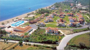 An aerial view of a coastal residential area with houses, a swimming pool, and a beach.