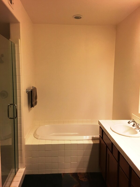 A small, modern bathroom with a glass shower enclosure, a white bathtub, and a sink with a mirror.