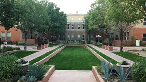 A courtyard with a central lawn, surrounded by brick buildings and trees.
