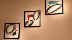 A living room with a white sofa, three framed abstract paintings, and a string of blue lights.
