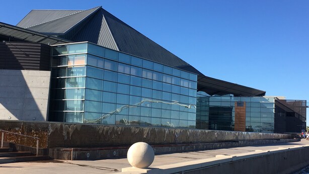 A modern building with reflective glass windows and a concrete structure.