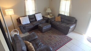A living room with a sectional sofa, a small side table with a lamp, and a patterned rug.