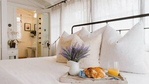 A neatly made bed with white linens, a tray with croissant and orange juice, and a lavender bouquet. - Carmel’s HIGHEST RATED and Most ROMANTIC Getaway - Walk to Beach and Town (Carmel)