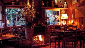 A cozy room with a fireplace, wooden furniture, and a window with a view of trees. - Carmel’s HIGHEST RATED and Most ROMANTIC Getaway - Walk to Beach and Town (Carmel)