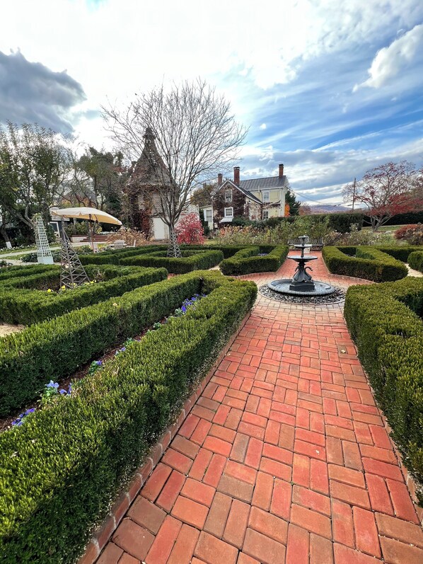A brick pathway leading to a fountain, surrounded by neatly trimmed hedges and a variety of plants. - The Inn 1 min walk to Entire Colonial 3BR House Fast WiFi  (Washington)