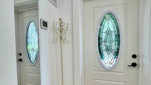 Un couloir avec une porte blanche, un grand miroir, un porte-manteau et un tapis à motifs.