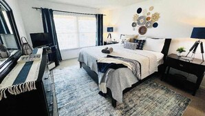 Ein Schlafzimmer mit Bett, Schreibtisch, Fernseher und Wandbild.