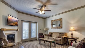 A living room with a fireplace, a ceiling fan, a television, and a large mirror. - Close to attractions - Inside and outside pool and hot tub! (Pigeon Forge)