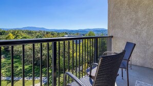 A balcony with wicker chairs, a view of a green landscape and distant mountains. - Close to attractions - Inside and outside pool and hot tub! (Pigeon Forge)