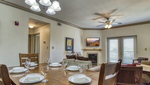 A dining area with a wooden table set for four, a ceiling fan, and a fireplace. - Close to attractions - Inside and outside pool and hot tub! (Pigeon Forge)