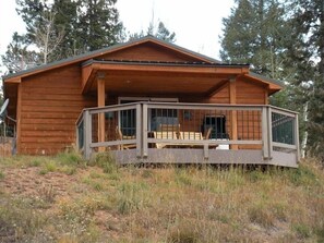 Una baita di legno con un portico coperto e una terrazza recintata.