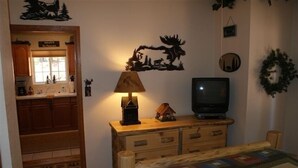 A cozy bedroom with a wooden dresser, a lamp, a television, and a bed with a quilt. - Altitude with Attitude-Awesome Mountain Cabin  (Divide)