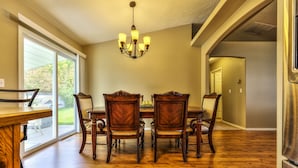 A dining area with a wooden table and chairs, a chandelier, and a view through large windows. - Single level 4 bdrm w/2 car garage, Golf Course only 200 yrds away!!! (Meridian)