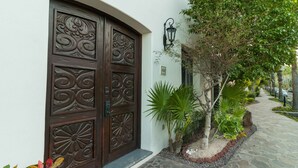 A stone-paved pathway leading to a decorative wooden door with intricate carvings.