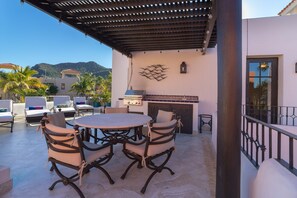Une terrasse extérieure avec une table ronde et des chaises, un barbecue et une vue sur les montagnes.