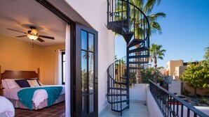 A bedroom with a bed, a ceiling fan, and a view of the outside.