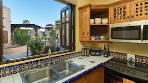 A kitchen with wooden cabinets, a stainless steel sink, a microwave, and a stove.