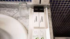 A bathroom sink with a marble countertop, two boxes of soap, and two packets of shower gel. - Negresco Gran Vía (Madrid)
