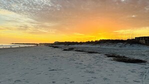 Ein Strand mit Fußspuren und einem Sonnenuntergang im Hintergrund.