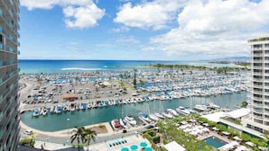 A marina with numerous boats docked, surrounded by buildings and a clear sky. - Deluxe Waikiki Ocean Front Suite - Ilikai (Honolulu)