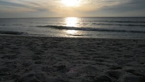 En strand med vågor och en solnedgång.