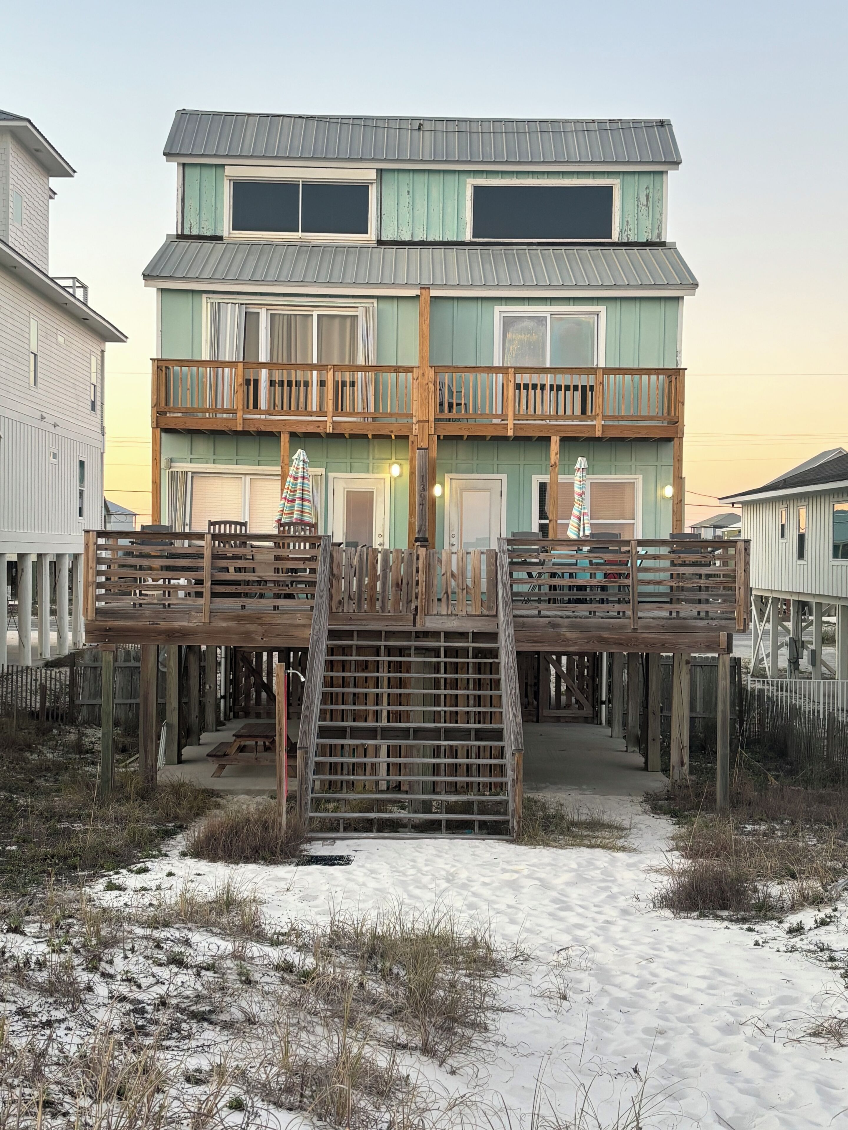 A two-story building with a wooden deck and a staircase leading to the upper level.