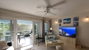 A living room with a TV, sofa, and a view of the outdoors. - Bijou! Sophistication and comfort in Turtle Cove (Providenciales)