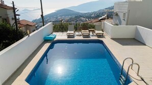 Una piscina al aire libre de temporada, sillones reclinables de piscina