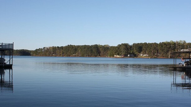 A calm lake with docks, a clear sky, and a forested shoreline.