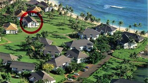 Oversigtsbillede af et kystnære boligområde med huse, en golfbane og en strand.