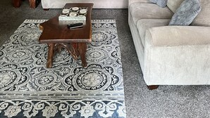 Una sala de estar acogedora con techo de madera, dos sofás, una mesa de centro y un tapiz estampado.