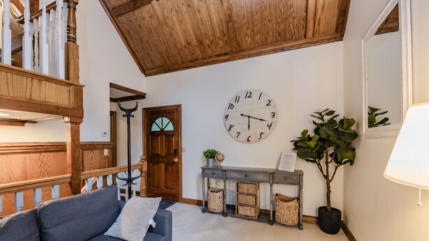 A living room with a wooden staircase, a grey sofa, a wall clock, a console table with baskets, and a potted plant. - Castle like home in SW PDX, close to downtown! (Portland)
