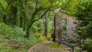 A brick building with a paved pathway leading to it, surrounded by lush greenery and trees. - Castle like home in SW PDX, close to downtown! (Portland)