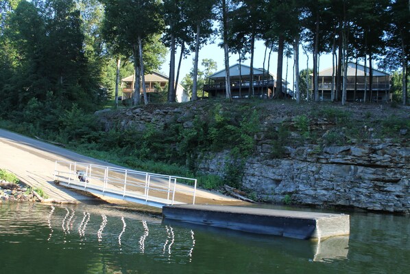 A riverside property with a dock, a bridge, and a building surrounded by trees. - Beautiful Lakefront Home-Walk to Ramp and Pool (Burnside)
