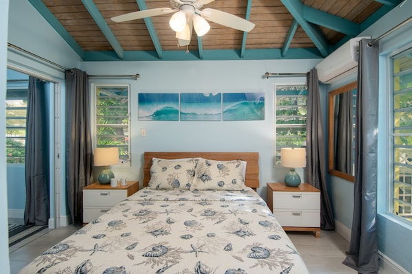 A bedroom with a bed, two nightstands, a ceiling fan, and a window with curtains.