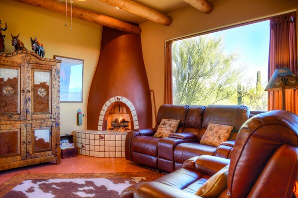 A cozy living room with a fireplace, leather sofa, and a rustic cabinet.
