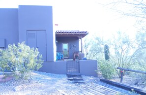 A building with a patio area, a door, and a small garden with plants.